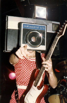 Frank wearing the camera headgear, "snapping pictures" of the audience while playing the song "Take My Picture Please"